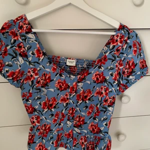 Blommig topp - Fin somrig topp som är köpt på Nelly. Säljer då den aldrig kommer till användning, den är i nyskick. 