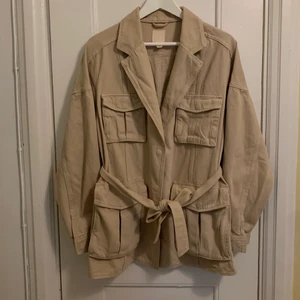 Workwear jacka - H&M workwear/safarijacka. Beige i 100% bomull. Knyt runt midjan om man vill eller ta bord bandet. Säljer enbart för att den är lite för stor. Men den är fin oversized för den som passar i den looken också. Så , flexibel i storleken. 