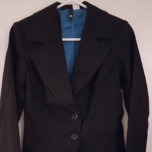 NY & OANVÄND Svart randig snygg kavaj med turkost foder. Storlek: 32/XS. - NY & OANVÄND Svart randig snygg kavaj med turkost satinfoder inuti. Storlek: 32/XS. Har 2 små fickor fram och själva kavajen stängs med knappar. Helt felfri. Lappar/tags sitter kvar sedan inköpet. FRAKT TILLKOMMER.