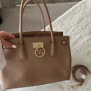 Guess väska  - En super snygg brun/beige guess handväska (äkta). Har använt typ två gånger och tillkommer en gistnat och Axelband. Axelbandet har en super liten skada men man ser inte den. Skriv för mer frågor eller om du är intresserad❤️