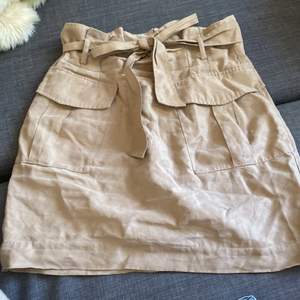 Kort kjol från H&M med knytning och fickor fram. I fint skick. Storlek 36.  Möts i Stockholm 