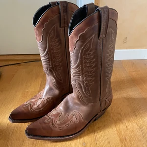 Bruna Cowboyboots - Jättefina bruna cowboyboots med snygga detaljer från Sancho Boots! Storlek 39/40! Kan mötas upp i Stockholm, annars står köparen för frakt💗