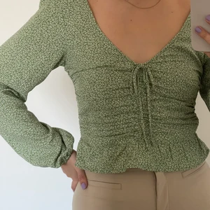 Grön blus  - Söt blommig blus från H&M. Endast använd 1 gång. Snörning vid bröstet (som inte går att dra åt) och volang längst ner.