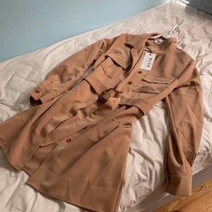 vår kappa beige brun na-kd - jättefin beige/brun kappa från na-kd, ganska tunn så passar perfekt till våren. storlek 38 så lite oversized, men man får plats med tjocktröjor och sånt under då. den är aldrig använd och prislapp finns kvar. pris kan diskuteras 