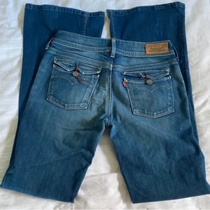 Lågmidjade Levis jeans - Ett par lågmidjade blå jeans som jag köpte på Plick men som tyvärr inte passade mig. De är ifrån Levis och har skitsnygga detaljer på fickorna. Midjemåttet är 84cm och innerbenslängden är 86. Köp inte direkt. Köparen betalar för frakten