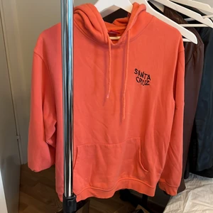 Santa Cruz hoodie - Köpt för ca 2 år sedan. Använd hyggligt mycket men än i bra skick! Snygg neonorange färg med ett coolt tryck på ryggen. Storlek medium och passar perfekt på mig som är 1.75 m lång. 