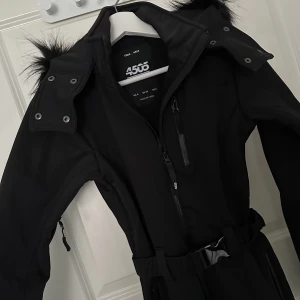Skidoverall  - Superskön och jättefin skidoverall från Asos! Använd 1 gång. Finns en liten skada på tyget som syns lite på sista bilden. Annars är den som ny!