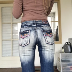 Y2k jeans - Bootcut jeans😍Bra skick men många Rhinestones har trillat av & dom rosa trådarna e lite slitna. Storlek 38, uppskattas till storlek W28/29. 79 cm runt midjan, 82 cm innerbenslängd. Jag är 176 cm och har W29 i jeansstorlek 💛Använd gärna köp nu-funktionen 🌟