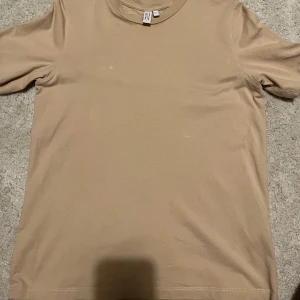 Beige T-shirt från & Other stories - Denna T-shirt är i ett otroligt mjukt material och är köpt på & other stories! Den är ganska lite använd men har fått två fläckar som syns på bild 2, därför säljs den för mindre 