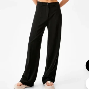 Tygbyxor - Svarta tygbyxor från BERSHKA! Strl 38. Mest bara legat i garderoben och säljs endast då jag har ett överflöd av liknande byxor! 🥰Frakt tillkommer.