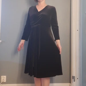 Klänning från Jumperfabriken  - Vacker höstklänning i mörkbrun sammetsvelour. Omlott i överdelen, tillhörande knytskärp. Nypris 1699:-