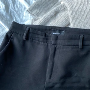 Svarta kostymbyxor - Svarta kostymbyxor köpta på Gina tricot för länge sedan i storlek 34. Använda mycket men fortfarande i väldigt fint skick. De svänger ut lite nedtill och passar någon som är runt 160cm i längd.