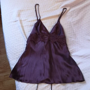 Lindex silkestopp strl xs - Mörklila topp med fina spetsdetaljer och snörning i ryggen från Lindex av Ella M i 100% silke. Justerbara band. Har små slits i sidorna med rosetter. Kuporna var lite för stora för mig, annars hade jag behållt det. 