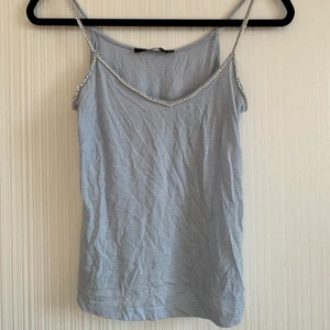 Linne med pärlor - Blått linne med pärlor. Finns ett litet hål fram på tröjan