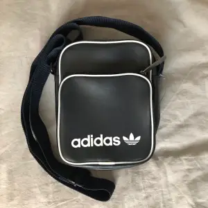 liten mörkblå/grå (nästan svart) väska från Adidas. köpt 2017 för ca 300 kr. sparsamt använd & i bra skick! justerbara band.