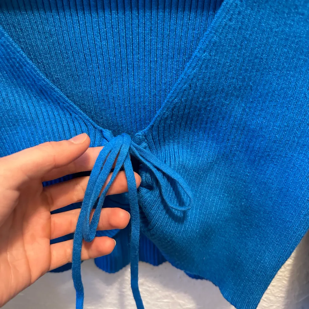 Croppad stickad tröja från Zara i jättegin blå färg med knytdetalj framtill som kan anpassas! Endast använd en gång så i superfint skick☺️. Toppar.