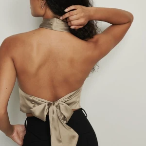 Topp med öppen rygg  - Ny & oöppnad med prislappen på! Fin beige satintopp i storlek 36/S. På bilden är den snurrad två gånger vid halsen, man kan göra en gång också vilket blir snyggare. Skriv för fler bilder, frågor, eller diskutera pris! Nypris 250 kr, säljer för 200 kr