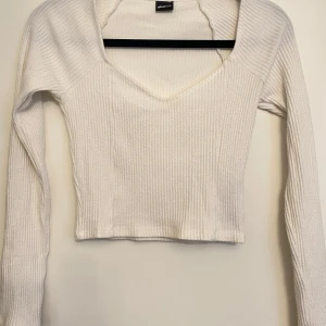 Vit ribbad tröja från Gina Tricot - Säljer en stilren vit ribbad tröja från Gina Tricot. Tröjan har en v-ringad design och långa ärmar, perfekt för en chic och bekväm look. Passar utmärkt till jeans eller kjol för en avslappnad stil. Perfekt för både vardag och speciella tillfällen. Gina tricot storlek Xs säljer den även i svart