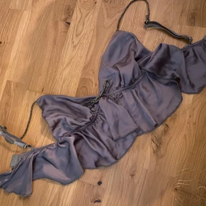 Volangtopo - Superfin topp men glitter vid rosetten och på banden. Aldrig använd, är en storlek M men skulle säga att den är som en XS/S. Färgen är grågrön