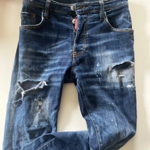 Blå jeans från Dsquared2 - Snygga blå jeans från Dsquared2 med slitna detaljer och en cool, distressed look. De har en knappgylf och klassisk femficksdesign. Perfekta för en avslappnad stil med en touch av edge.