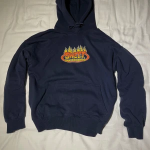 Mörkblå hoodie från Sweet Skateboards - Säljer en mörkblå hoodie från Sweet Skateboards med ett färgglatt tryck på framsidan. Hoodien har en loose passform med långa ärmar och en stor ficka framtill. Den är S men är pösig så passar även M 
