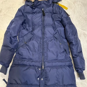 Blå dunjacka från Parajumpers - Säljer en blå dunjacka från Parajumpers, perfekt för kyliga dagar. Jackan har en dragkedja framtill och praktiska fickor. Den är långärmad och har en huva med detaljer i gult. En del av Masterpiece Series. Köparen står för frakten och pris kan diakuteras!!💕