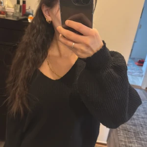 Svart stickad tröja - Säljer en stilren svart stickad tröja med långärmad design. Perfekt för kyligare dagar och enkel att matcha med olika outfits. Tröjan har en klassisk passform och är ett måste i garderoben.