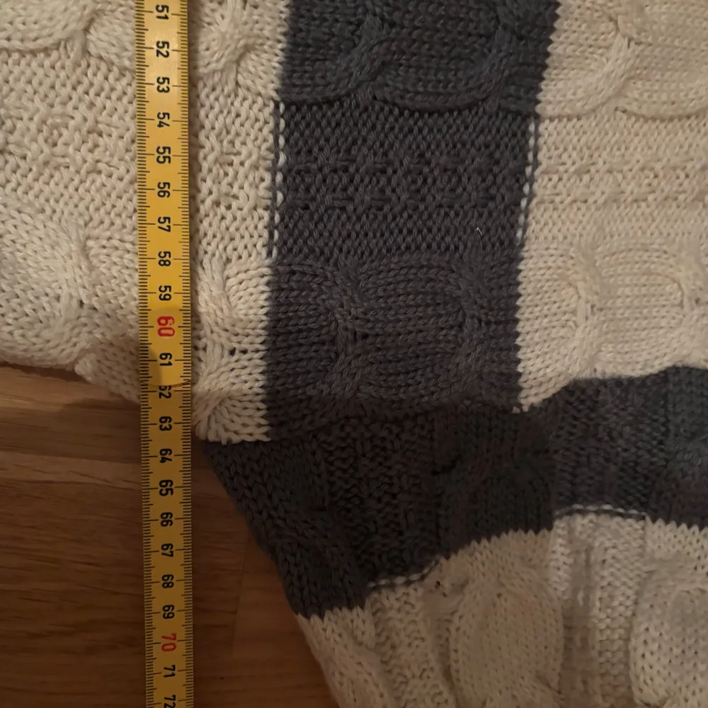 Säljer en snygg stickad tröja från Matinique i grått och beige. Tröjan har ett randigt mönster med kabelstickade detaljer och ribbade muddar vid ärmslut och nederkant. Perfekt för kyligare dagar!. Neuletakit & Villapaidat.
