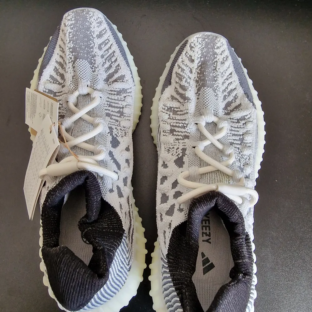 Snygga Adidas Yeezy sneakers i en stilren grå och vit färgkombination. Skorna har en stickad ovandel med ett unikt mönster och bekväm snörning. Den ribbade sulan ger både stil och komfort.Har order bekräftelse från Adidas för att bevisa att de är äkta.. Kengät.