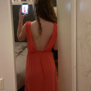 Korallfärgad balklänning  - Snygg korallfärgad bak klänning med öppen rygg💕✨Använd 1 gång💕Klänningen har en luftig passform och är tillverkad i ett lätt material som ger en skön känsla. Går ända ner till marken för mig som är 168🤍