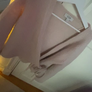 Omlottkofta COS - Säljer en ljusrosa kofta från COS. Den har en omlott-design med knytband i midjan och långa ärmar. Den strl s men har krympt i tvätten så den sitter mer som xs nu. Tröjan har blivit lite missfärgad i tvätten men ser ändå bra ut, kontakta för fler bilder om du är intresserad💗