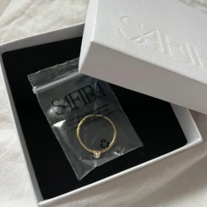 Oanvänd guld ring med vit pärla från Safira - 18K guldpläterat sterling silver. Aldrig använd och kommer i sin original förpackning. Ordinarie pris är 399 kr. Storlek 18