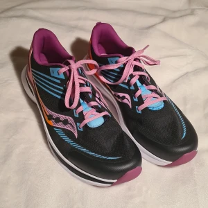 Svarta Saucony Kinvara 12 löparskor - Snygga Saucony Kinvara 12 löparskor i svart med rosa snörning och blå detaljer. Skorna har en lätt och luftig design med textilöverdel och en bekväm passform. Perfekta för löpning och träning. Skorna är aldrig använda, endast provade! Nypris 699kr