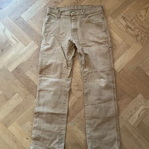 Beige carpenterjeans från Dickies - Säljer ett par klassiska beige carpenterjeans från Dickies. Byxorna har flera praktiska fickor och en rak passform.