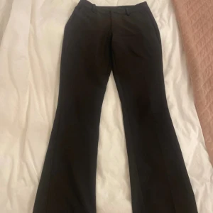 Svarta kostymbyxor - Snygga svarta kostymbyxor med en klassisk design. De har en rak passform och är perfekta för en stilren look. Byxorna har hällor för bälte och diskreta fickor både fram och bak. 