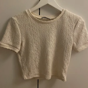 Vit stickad topp från Zara - Säljer en söt vit topp från Zara med korta ärmar och ett fint mönster. Toppen är croppad och har en rund hals. 💞💞💞