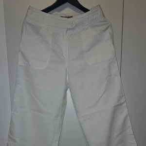 Vita vida byxor - Snygga vita byxor med en vid passform. De har en hög midja och är tillverkade i ett bekvämt bomullsmaterial. Perfekta för en stilren look.