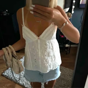 Zara topp - Vit broderad linnetopp från Zara! Säljer en söt vit linnetopp från Zara med tunna axelband och v-ringning. Toppen har vackra broderade detaljer och en liten rosett framtill. Perfekt för varma sommardagar! Endast använda en gång