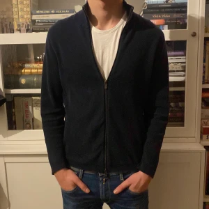 Mörkblå tröja med dragkedja från Massimo Dutti - Snygg och stilren mörkblå tröja från Massimo Dutti med dragkedja. Perfekt för en avslappnad men ändå elegant look. Tröjan har en hög krage och långa ärmar, vilket gör den idealisk för kyligare dagar.