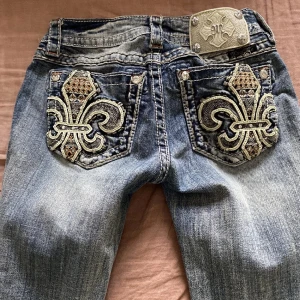Blå jeans med broderade detaljer från Miss Me - Snygga blå jeans från Miss Me med unika broderade detaljer på bakfickorna. Jeansen har en låg midja och är om sydda från skinny till bootcut. skriv privat vid frågor