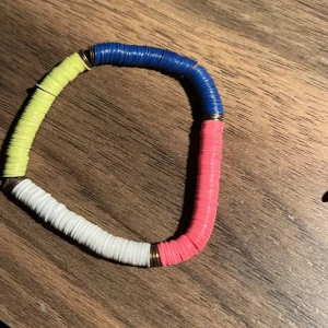 Färgglatt armband med runda pärlor - Säljer ett färgglatt armband med runda pärlor i blått, gult, vitt och rosa. Perfekt för att liva upp vilken outfit som helst! Armbandet har en elastisk tråd för enkel passform.