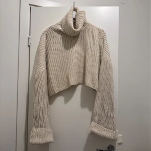 Stickad croppad tröja - Croppad tröja med hög hals och vida lösa armar. Sitter superfint.  Använd enstaka gånger så är i mycket bra skick utan skavanker. Storlek står ej men skulle säga XS-S
