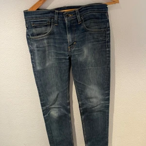 Levi's 511 jeans - Snygga Levi's 511 jeans i en klassisk blå färg. De har en slim passform och är tillverkade av bomull med en liten del polyester och elastan för extra komfort. Perfekta för en stilren look med fem fickor och knappgylf.