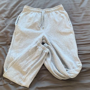 Grå mjukisbyxor från SOC - Säljer ett par grå mjukisbyxor från SOC i storlek S. Byxorna har elastisk midja med snörning och muddar vid bensluten. Perfekta för en avslappnad dag hemma eller lätt träning.