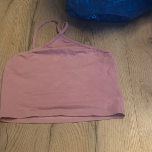 Rosa croppad linnetopp från H&M - Säljer en söt rosa croppad linnetopp från H&M Divided. Toppen har smala axelband och en enkel design som passar perfekt till sommaren. Perfekt för en avslappnad stil!