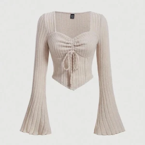 Beige ribbad topp  - Säljer en beige ribbad topp från  med lång ärm och knytning framtill. Toppen har en croppad passform och v-ringad hals. Perfekt för en stilren look!