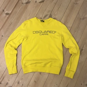 Gul sweatshirt från Dsquared2 - Säljer en cool gul sweatshirt från Dsquared2 med texten 'CAPRI' på bröstet. Tröjan har långa ärmar och en klassisk rund halsringning. Perfekt för en färgglad och stilren look! Passar som Xs-S  . Är öppen för bud