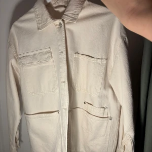 Beige overshirt med knappar - Snygg beige overshirt/jacka med knappar och två stora bröstfickor. Perfekt för lager-på-lager-stil. Långärmad design med klassisk krage och knappdetaljer vid ärmslut. Köpt för 499kr 1 år gammalt 