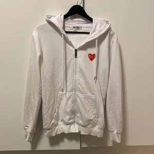 Vit hoodie Cdg Play - Säljer denna vita zip hoodie från cdg play då den inte längre passar mig. Tröjan ser lite skrynklig ut på bilderna men är i mycket fint skick. Kom privat för fler bilder eller funderingar