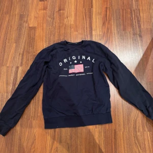 Mörkblå sweatshirt från Marqy  - Säljer en snygg mörkblå sweatshirt från Marqy med tryck framtill. Tröjan har långa ärmar och en klassisk rund halsringning. Perfekt för en avslappnad stil. 